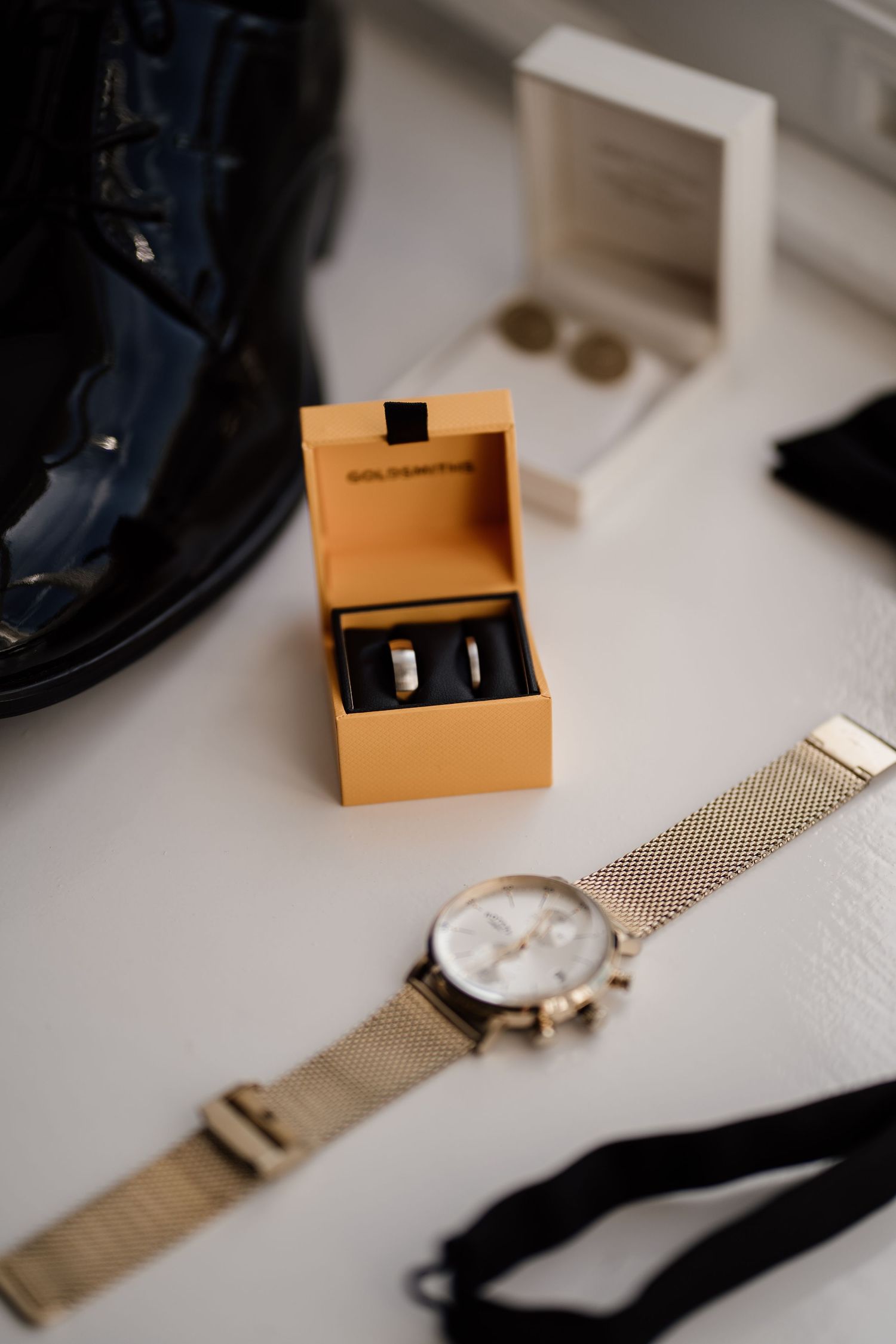 Grooms wedding day details featuring shoes, rings, watch and bow tie.