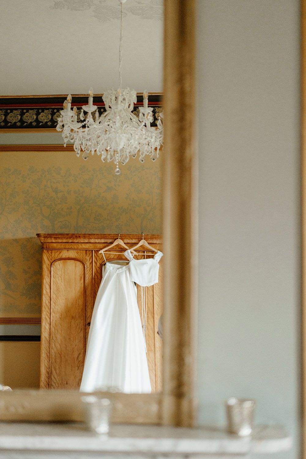 Wedding dresses hung on wooden wardrobe on her wedding morning at Rise Hall.