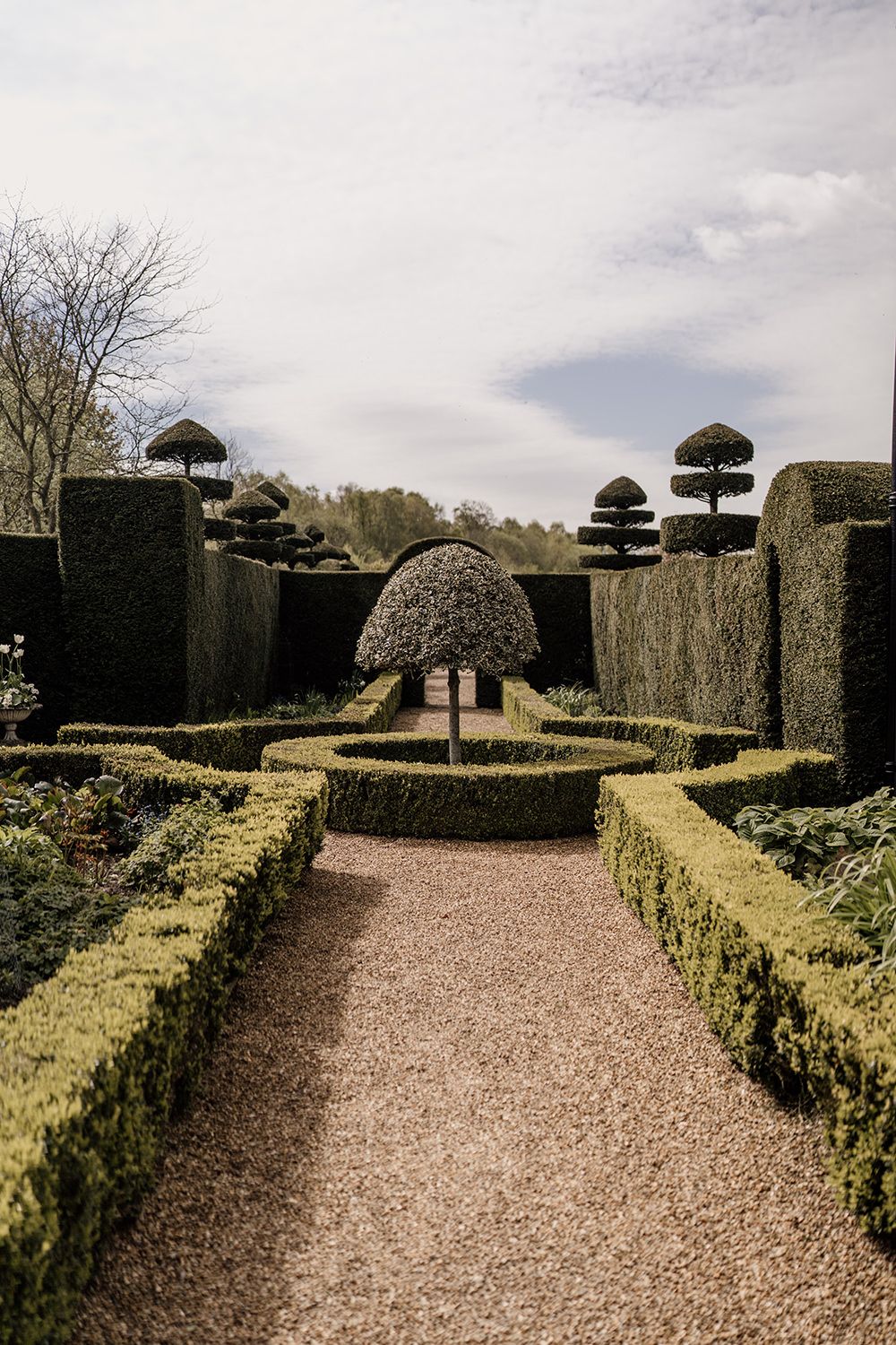 Gravel path with green bushes either side in the gardens at The Holford Estate.