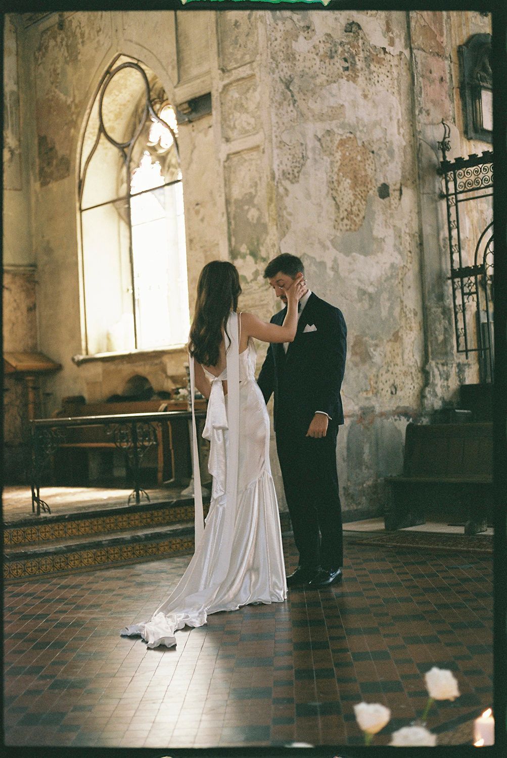 A couple shares an intimate dance moment in a historic stone church interior with arched windows.