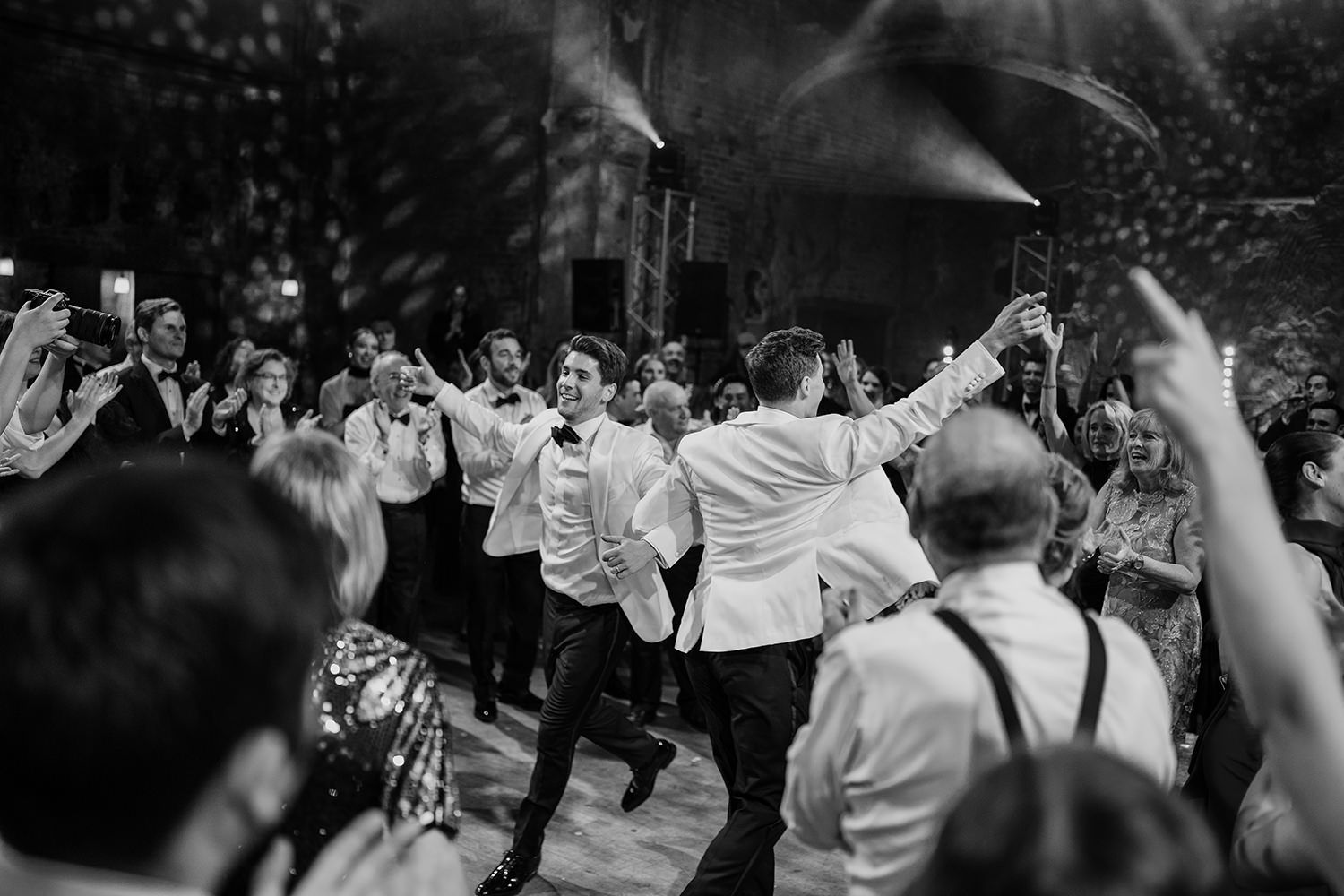 Guests dancing and performing during the hora at Battersea Arts Centre while the two grooms are in the centre.