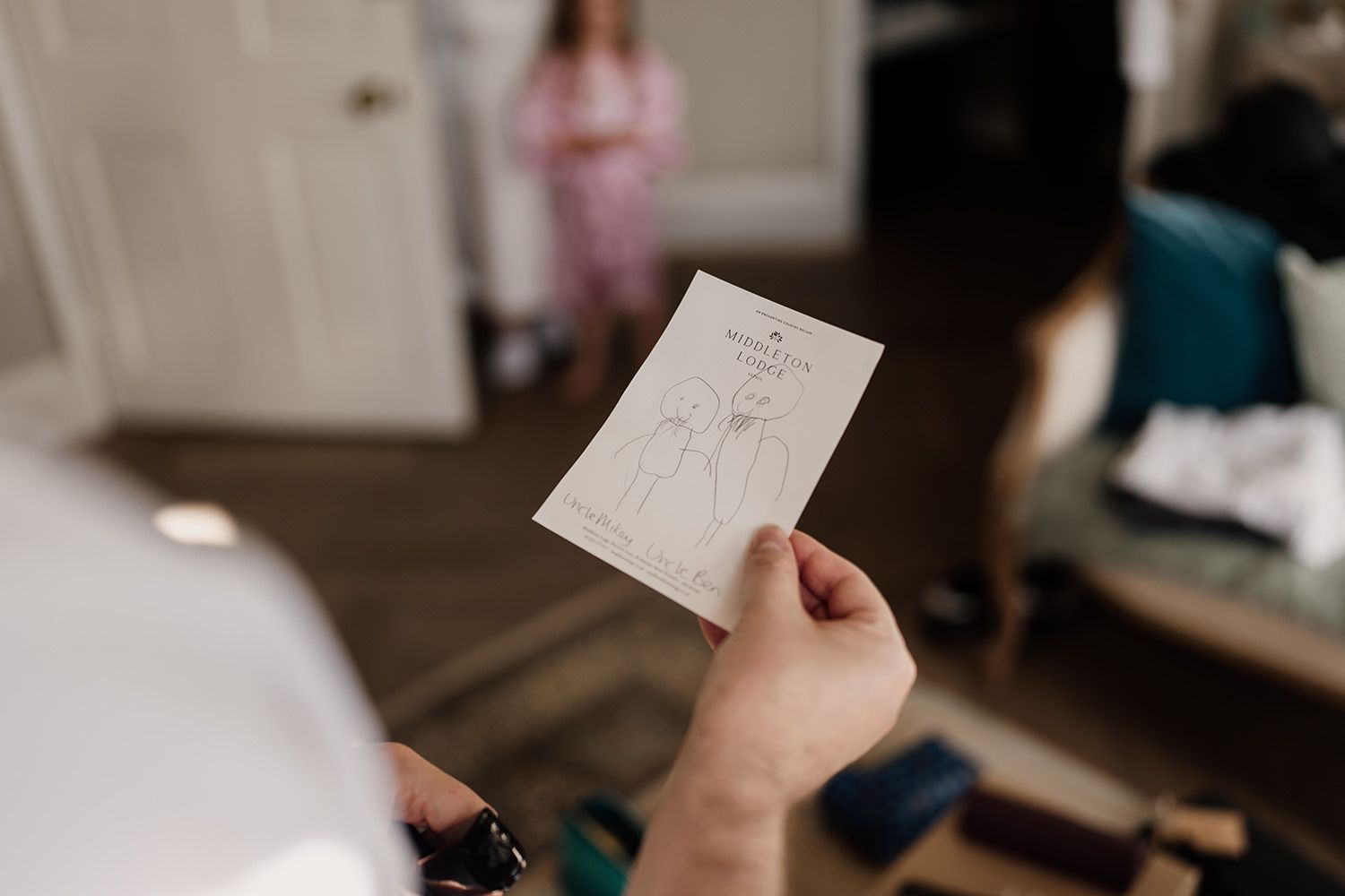 Groom holding a drawing from his niece on his wedding morning of himself and his future husband.