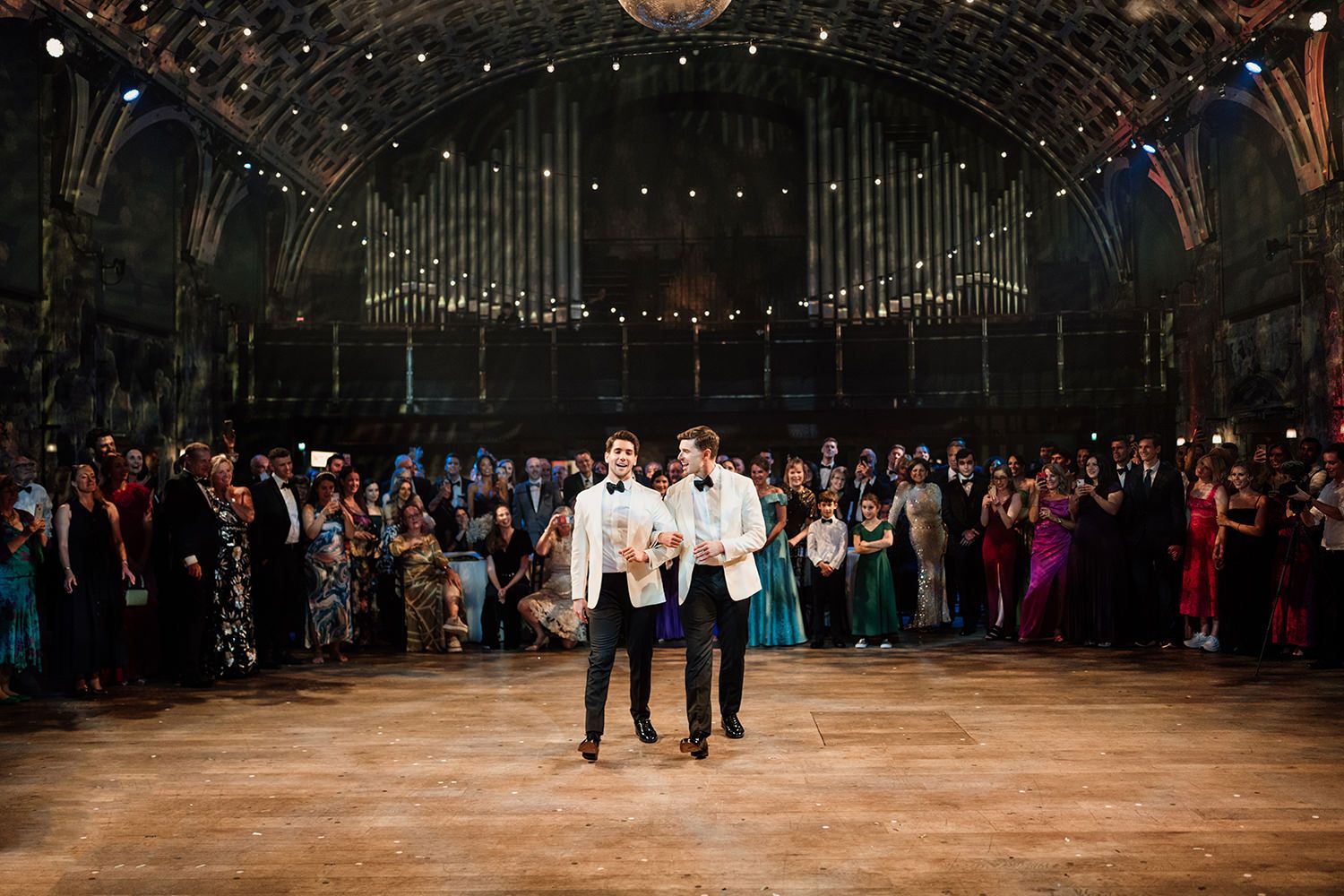 Guests watching two grooms perform their first dance at Battersea Arts Centre.