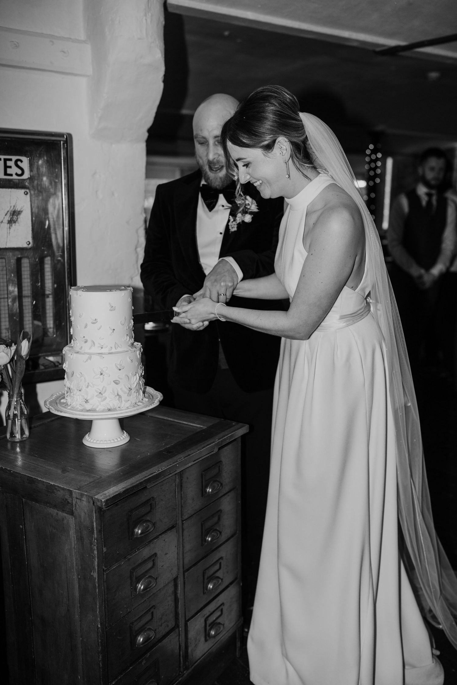 Couple cutting their elegant white wedding cake together at reception.