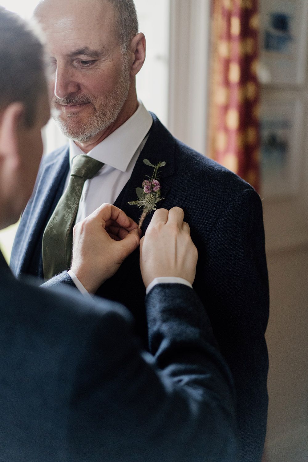 Groom adjusting button hole on groomsmen.