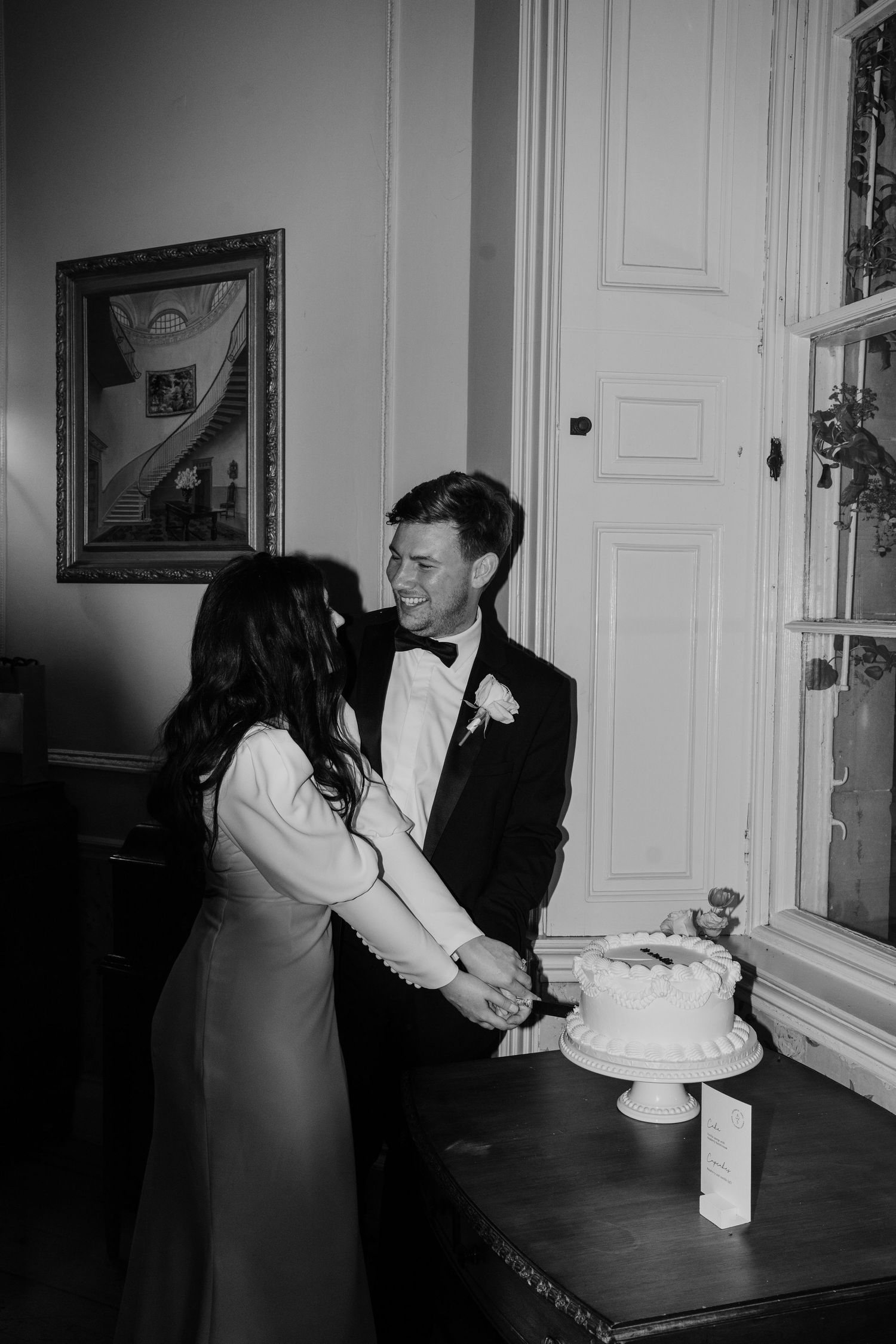 Couple cutting their wedding cake and looking towards eachother at Middleton Lodge Estate.