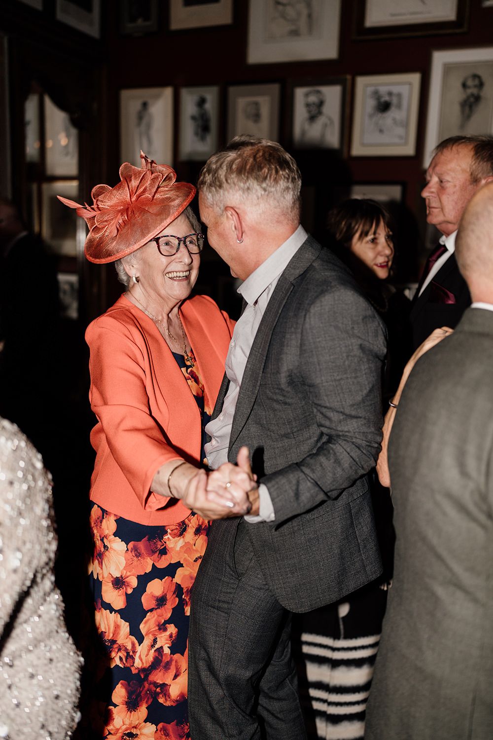 Dancing couple in formal attire enjoy a moment at a social gathering.