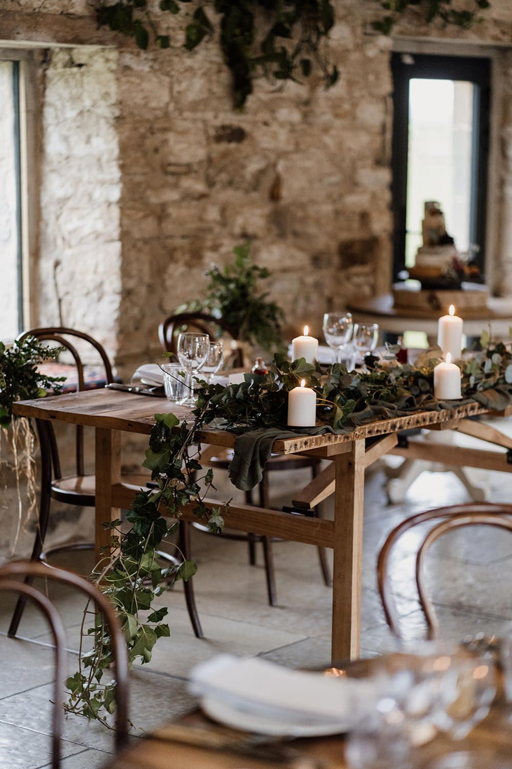 Wedding top table at Healey Barn decorated with flowers, greenery, candles and wine glasses.