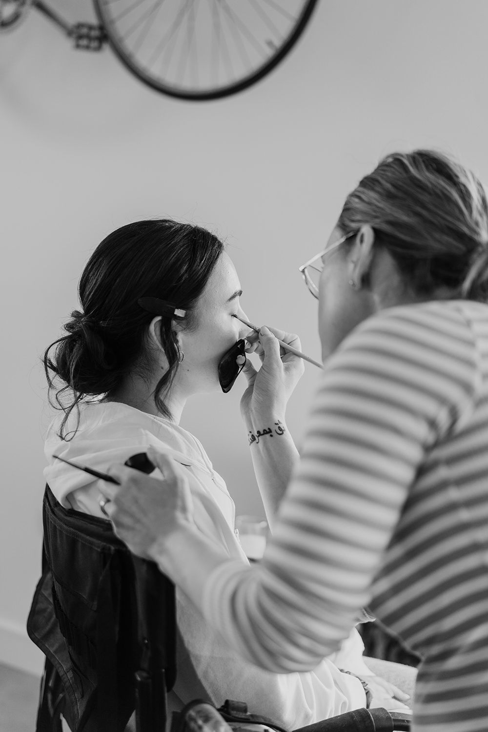 A makeup artist applies cosmetics during wedding preparations.