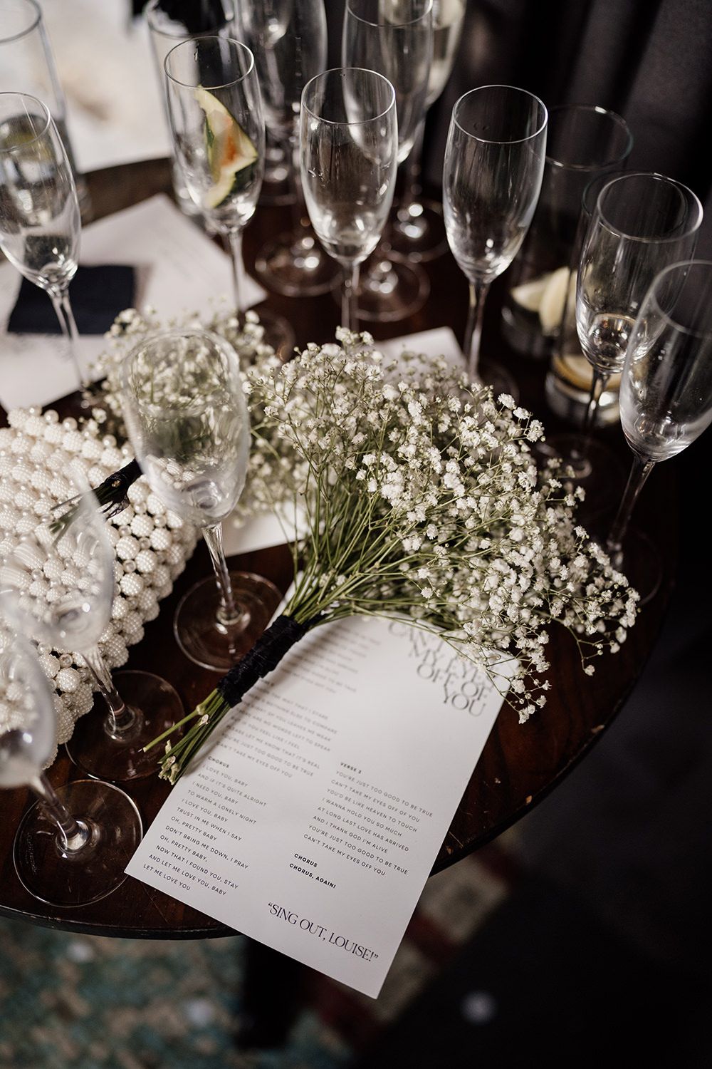 Wedding timeline and stationery on a table with empty champagne glasses and white flowers.