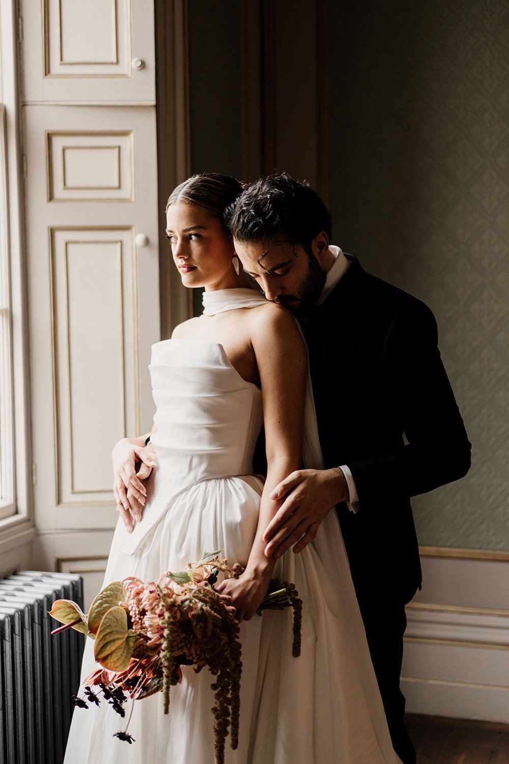 Editorial wedding portrait session: Bride and groom holding hands while looking towards each other.