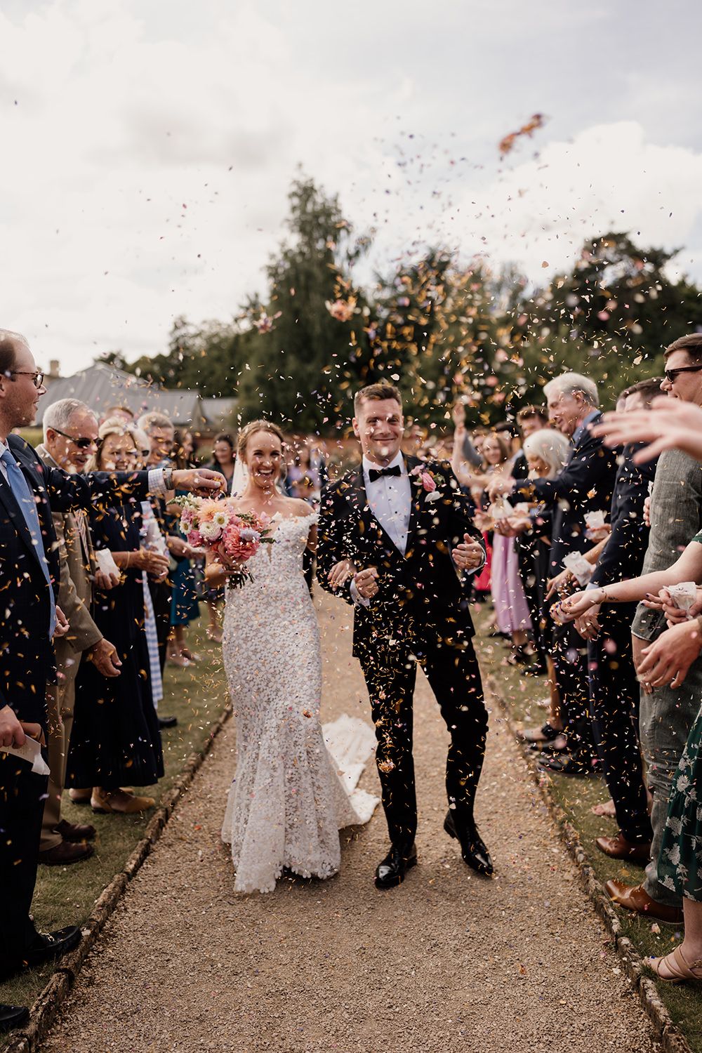 Bride and groom walking through confetti after getting married in The Garden Rooms at Kin House.