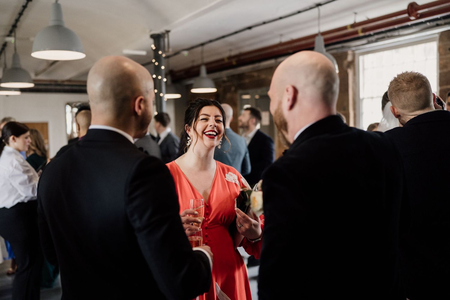 Guests in formal attire enjoying conversation at an indoor gathering.