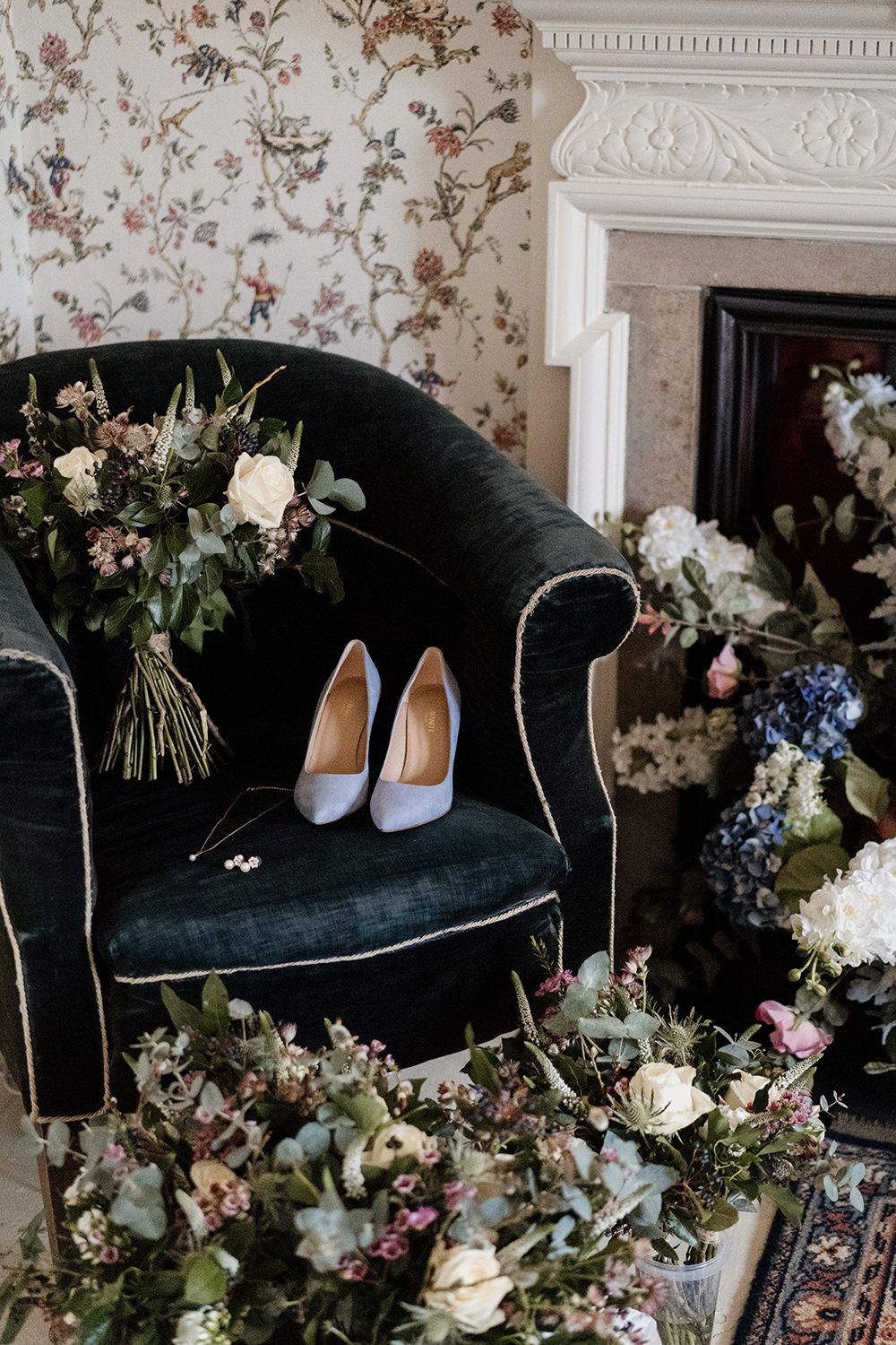Wedding shoes and jewellery on chair with flowers surrounded.