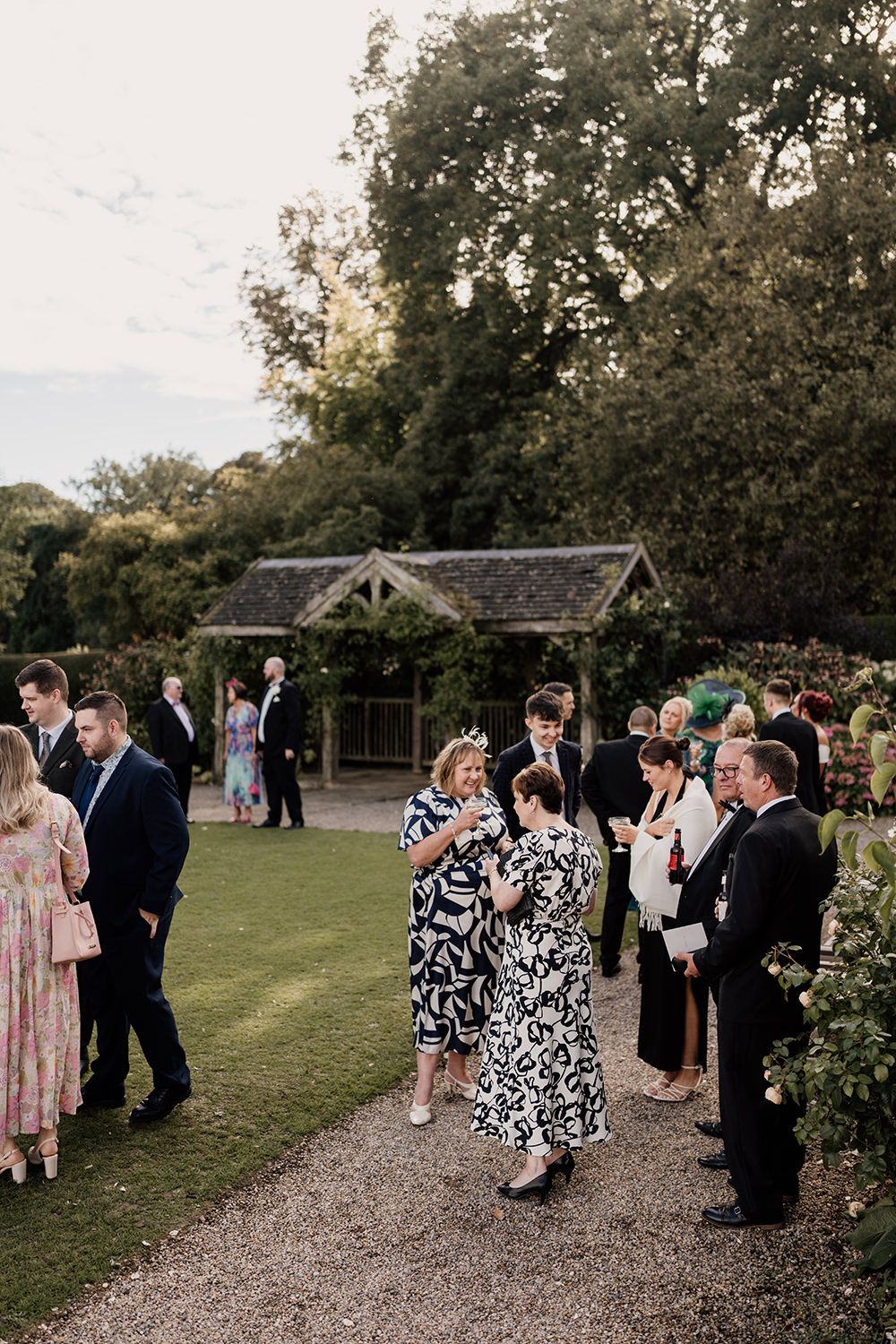 Candid wedding photography: guests enjoying cocktails on the lawn of this luxury UK wedding venue.
