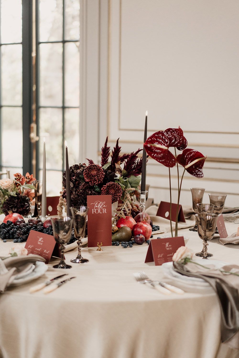 Wedding reception table detail featuring autumnal fabrics, red and burgundy flowers and candles.