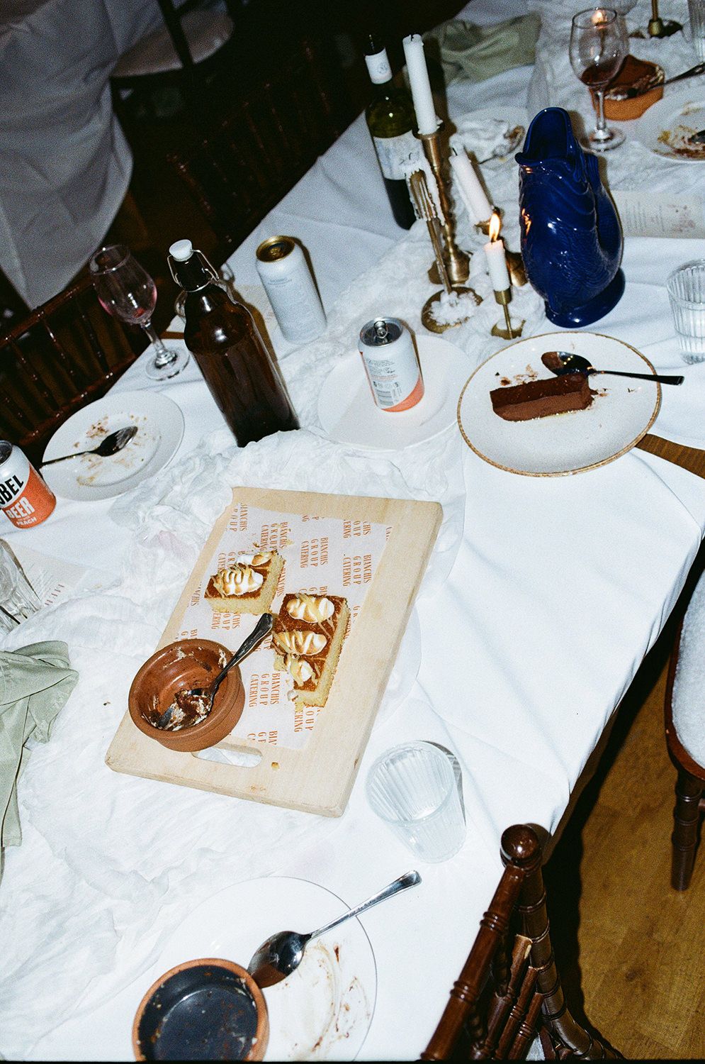 Multiple place settings at a formal dinner table with white tablecloths and wine glasses.