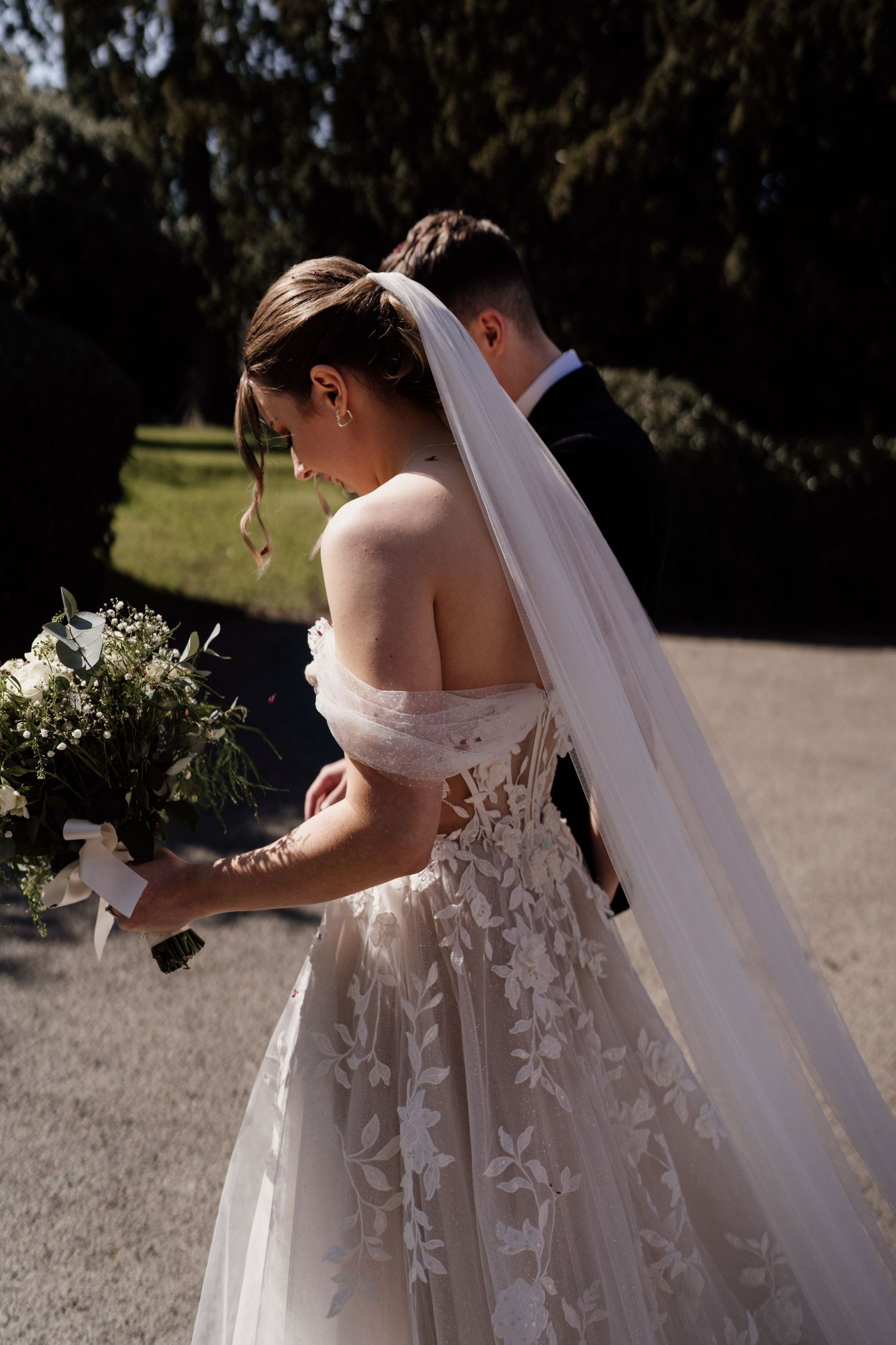 Detail of the brides dress as she walks through a courtyard.