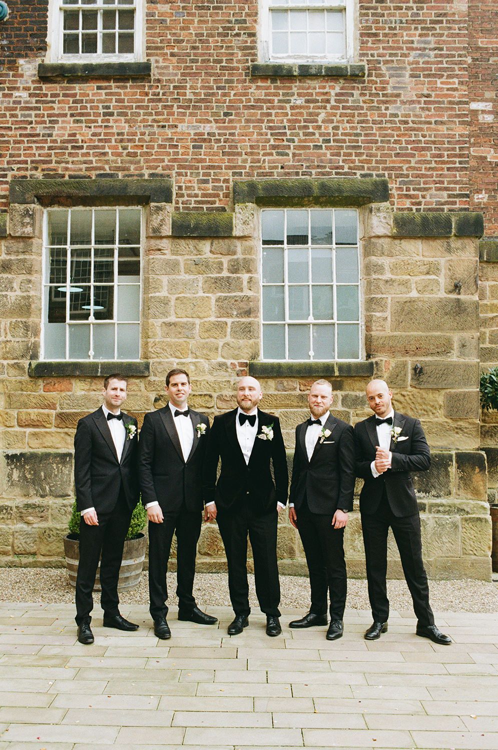 Groom and groomsmen dressed in black tie smiling and laughing.