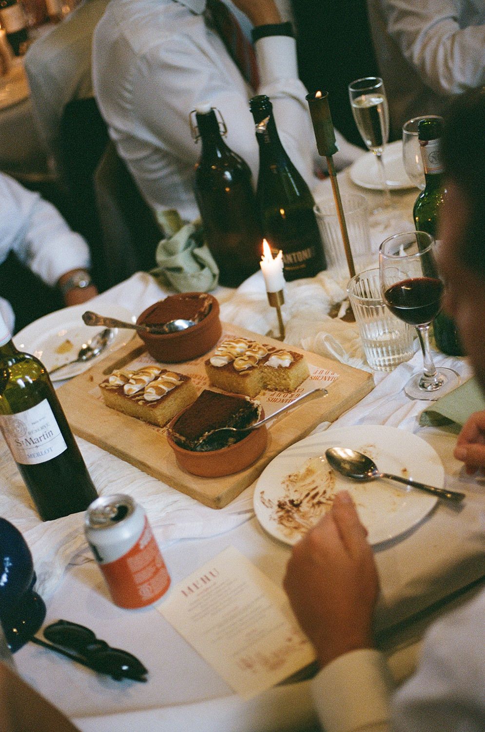 Wine tasting table setup with wooden serving boards, glasses, and tasting notes on white tablecloth.