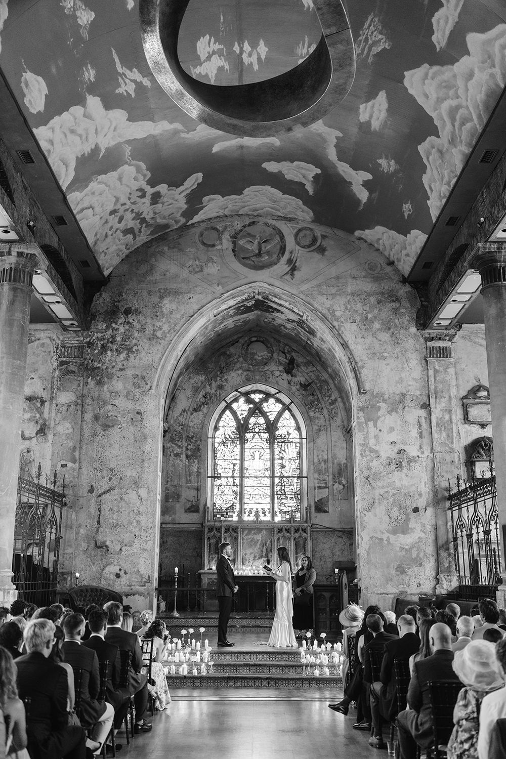 Black and white panoramic view of a church interior with guests seated in rows during a formal ceremony.
