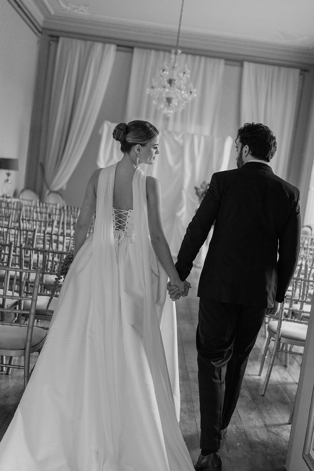 Bride and groom holding hands walking into their wedding ceremony at Rise Hall.
