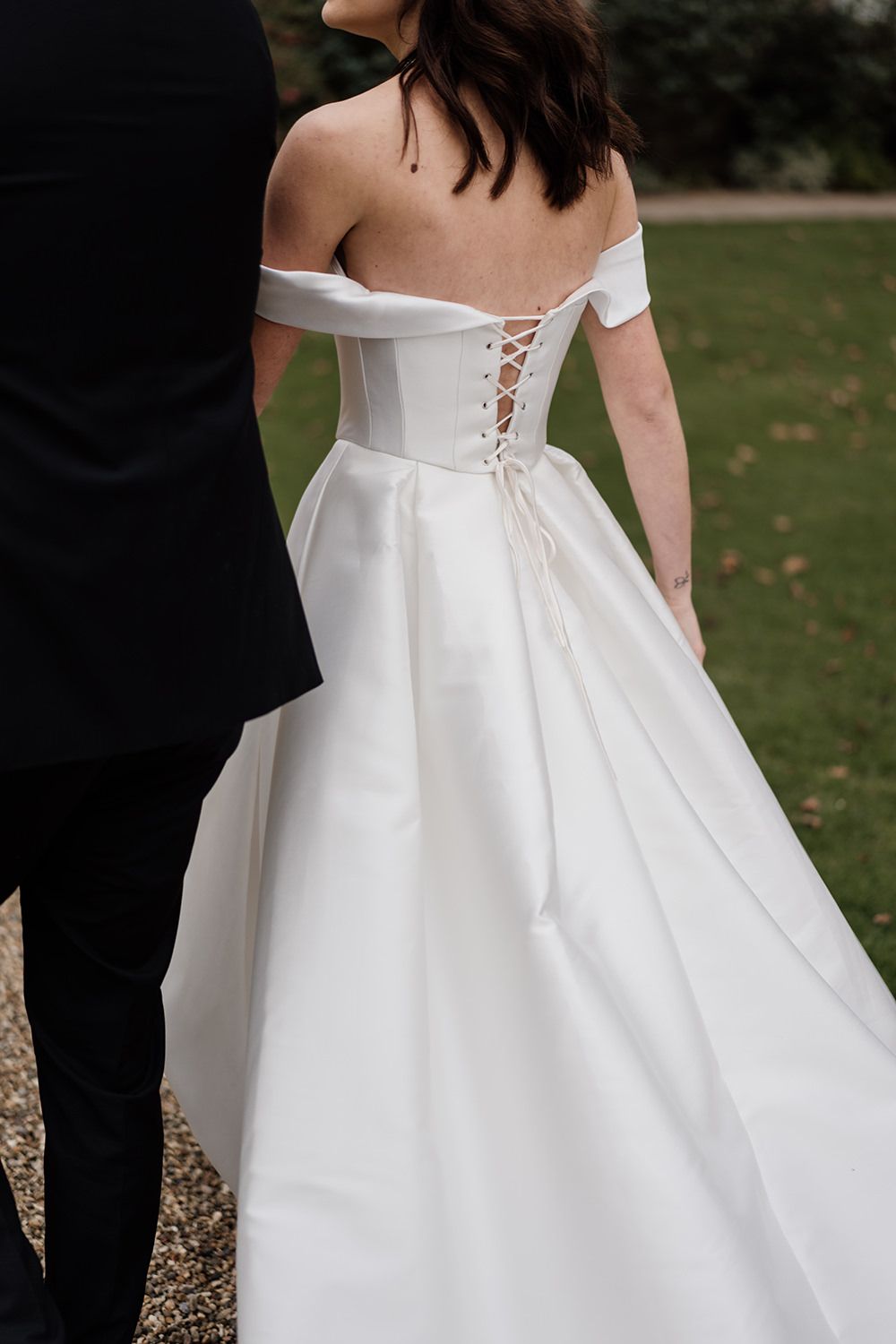 A detail photograph of a bride and groom holding hands, smiling, laughing while working through the grounds of Rise Hall.
