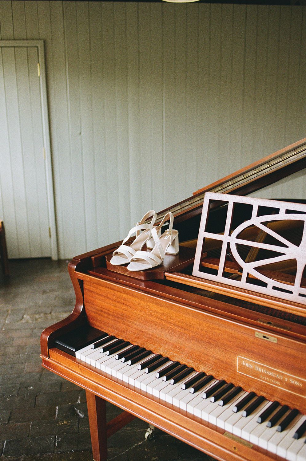 White wedding shoes on the corner of a grand piano.