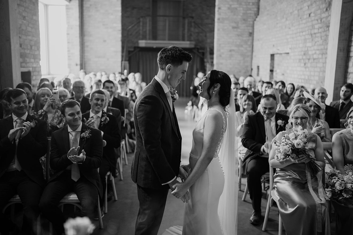 A wedding ceremony in progress with guests seated in rows at an indoor venue.