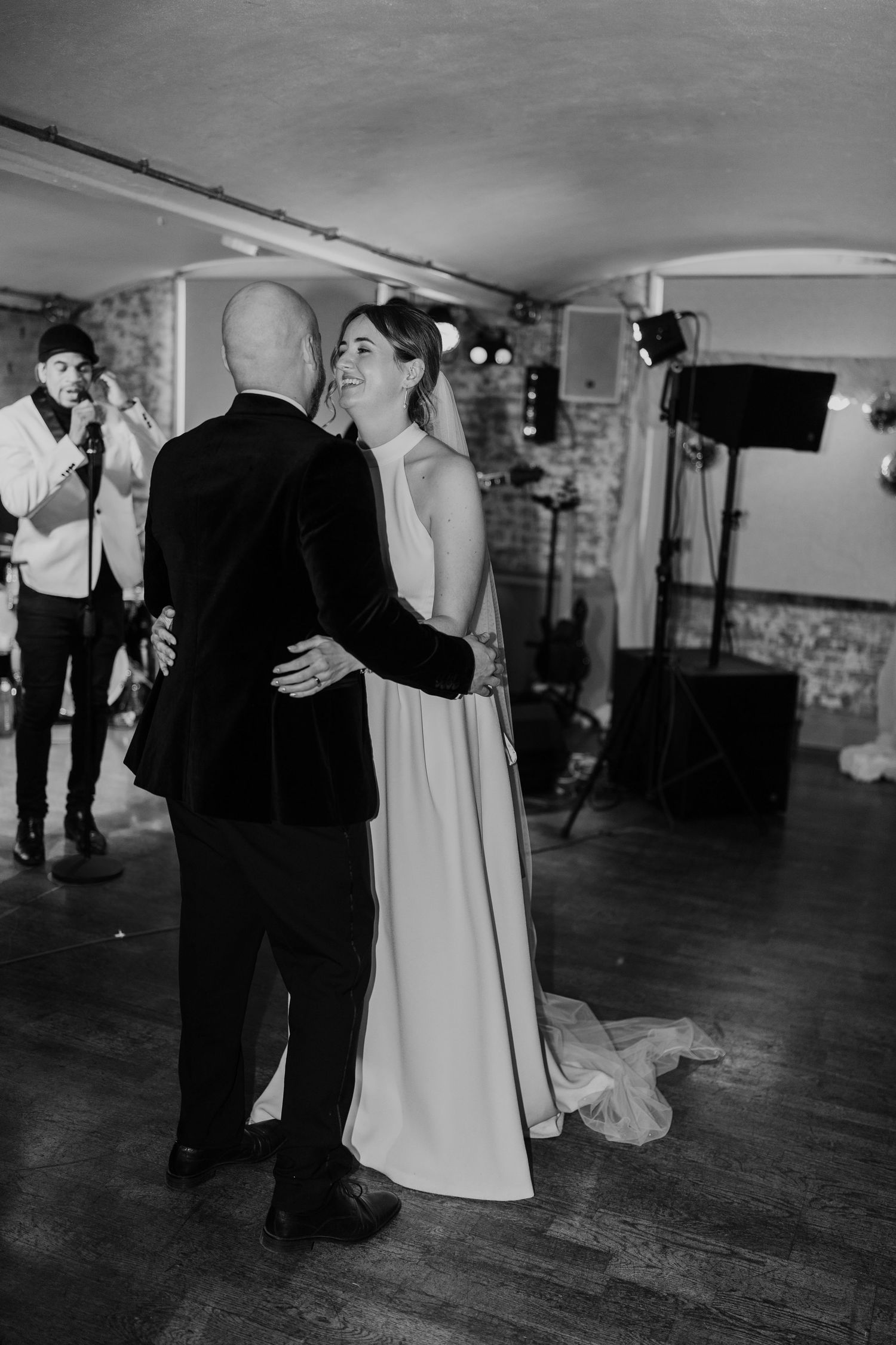 Couple sharing their first dance at wedding reception in rustic venue with live band.