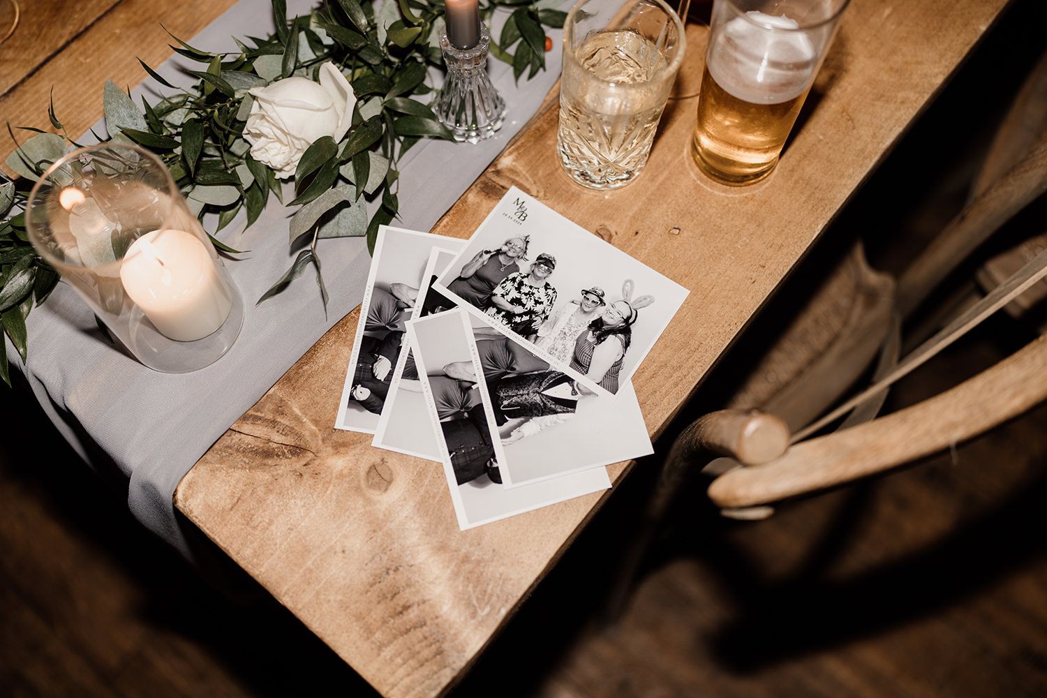 Candid wedding photography: table photograph with photobooth photos and glasses of wine.