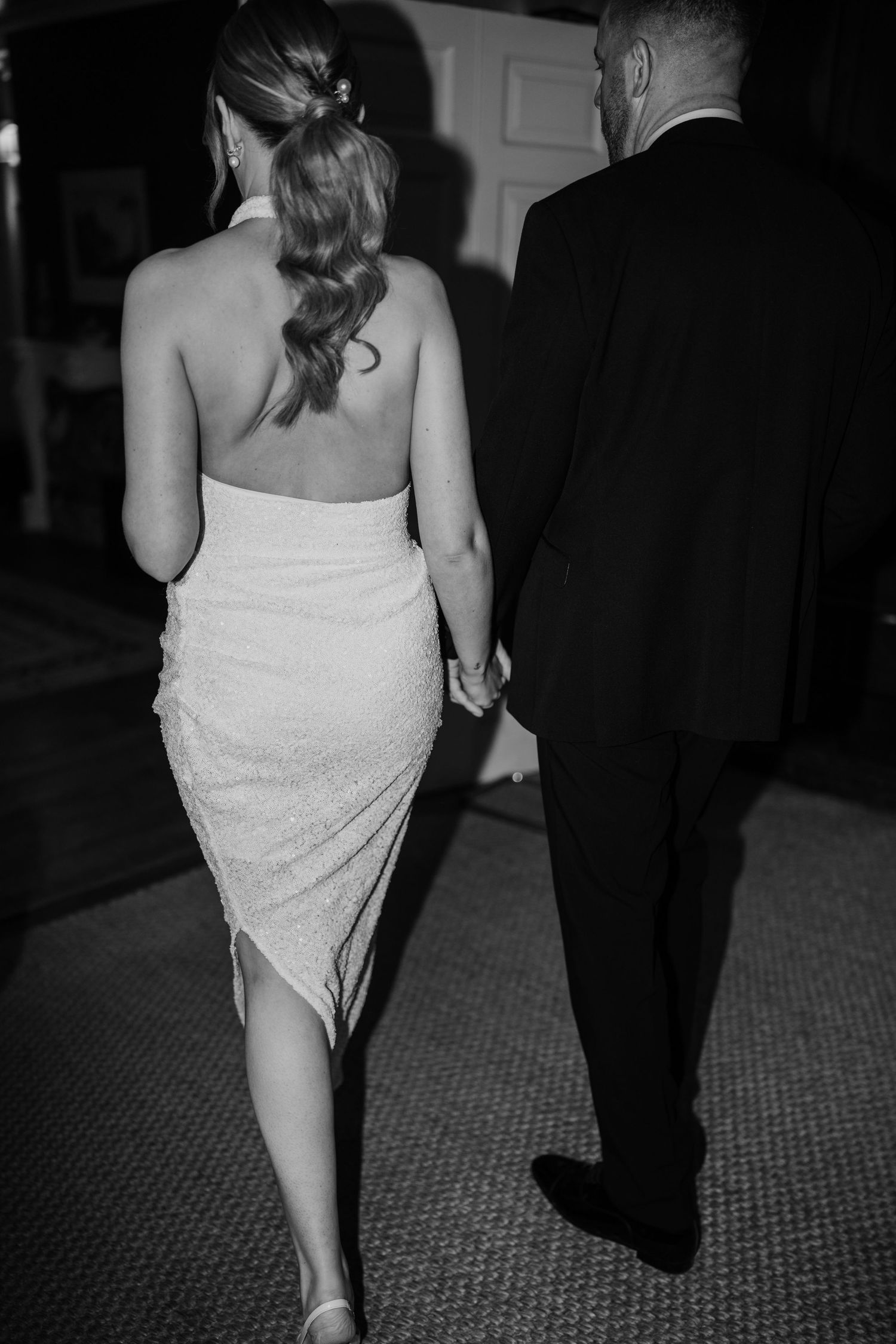 Black and white photo showing a couple walking together in formal attire.