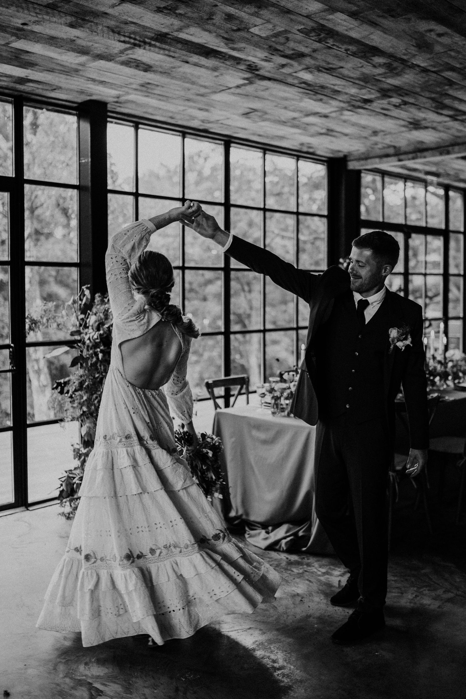 Bride being twirled by her husband on her wedding day in a wooden barn.