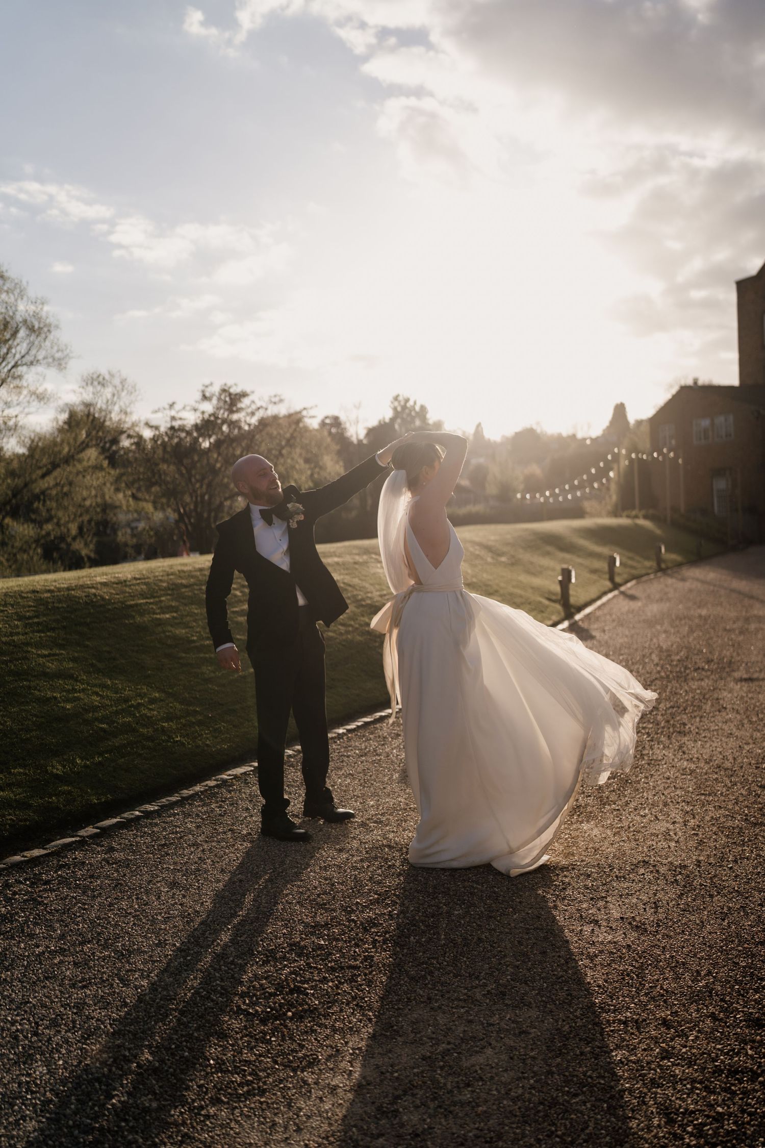 Sunset silhouette of couple with string lights and flowing dress creating romantic atmosphere.