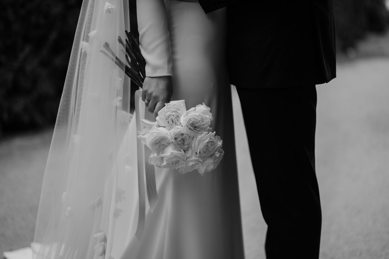 Black and white image of bridal flowers with the couple stood behind.