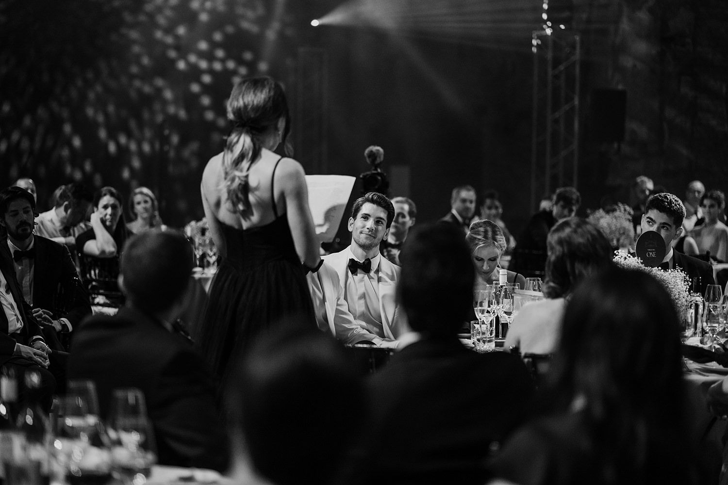 Grooms friend giving a speech at his wedding with guests and grooms listening and watching.