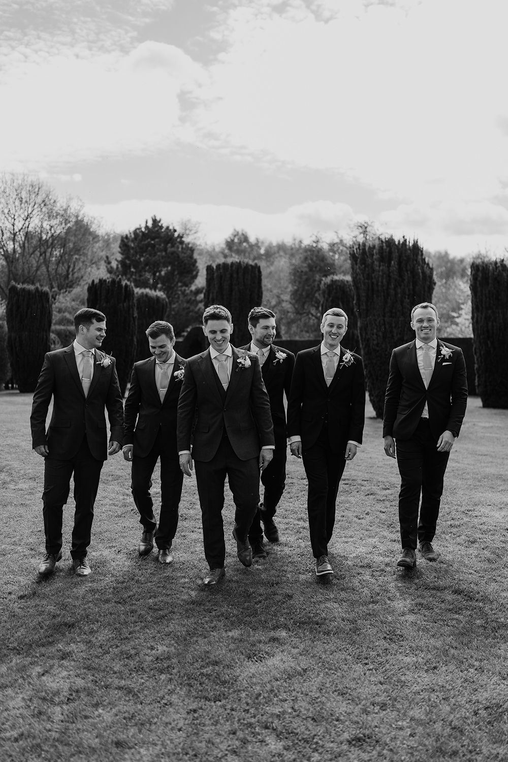 Groom and groomsmen walking through the gardens at The Holford Estate.