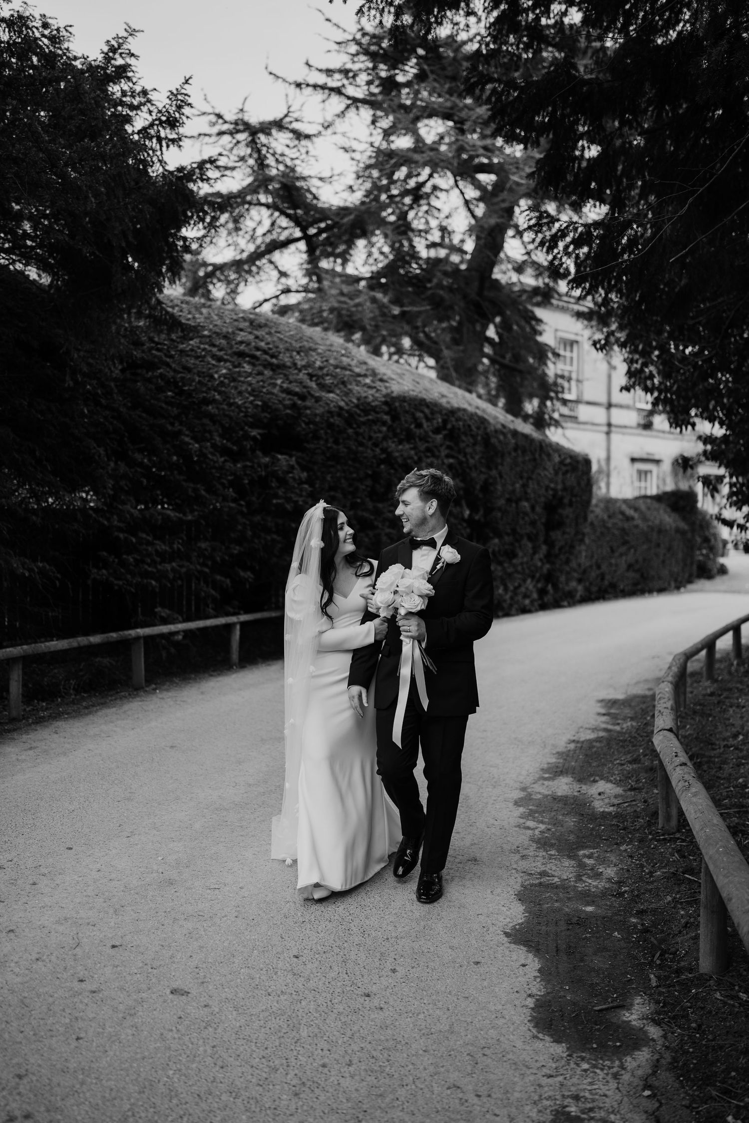 Black and white image of a couple walking on their wedding day.