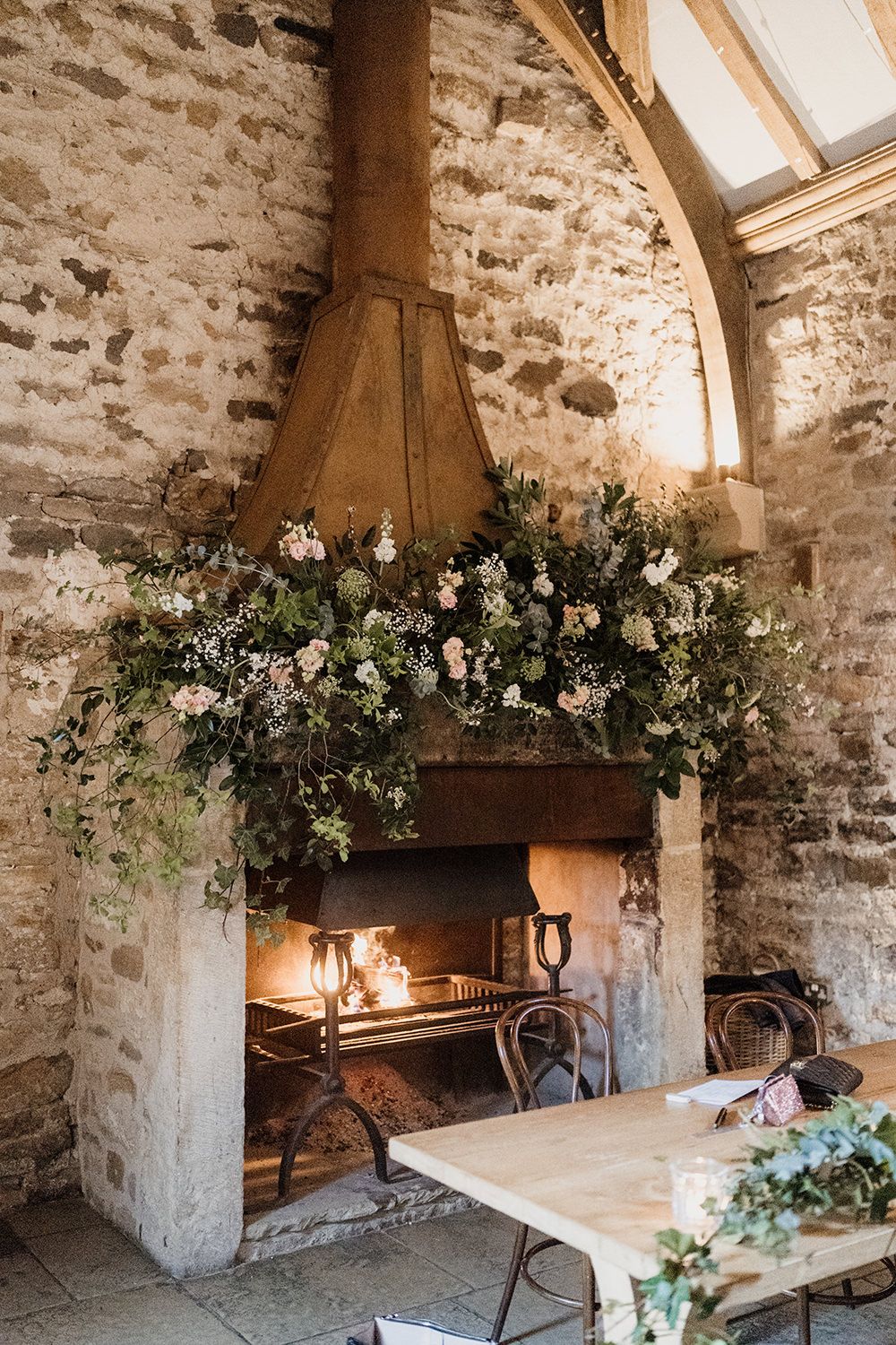 The main fireplace in Healey Barn decorated with flowers and wild greenery.