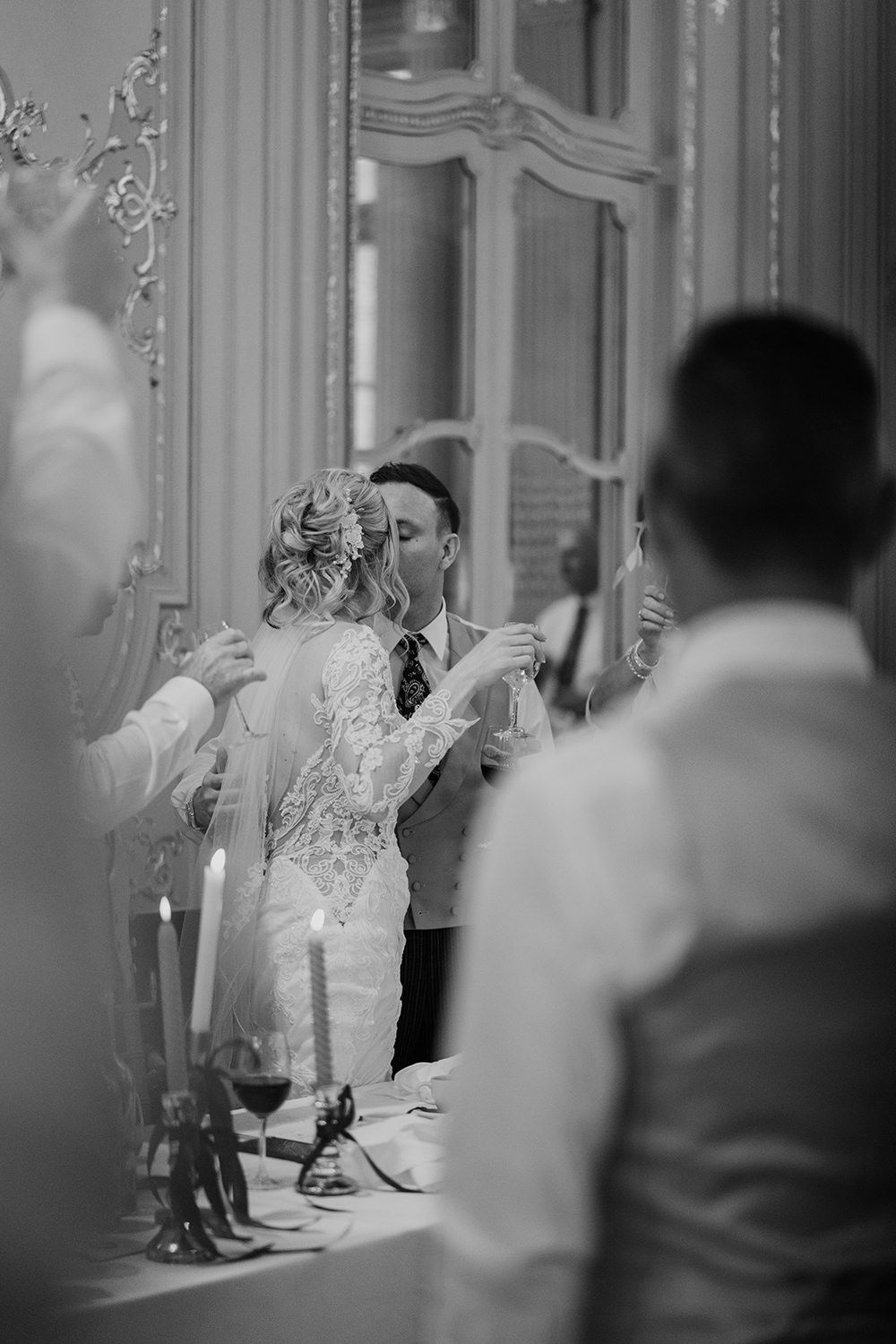 Black and white photo showing a bride dancing at an elegant wedding reception in an ornate room with decorative mirrors.