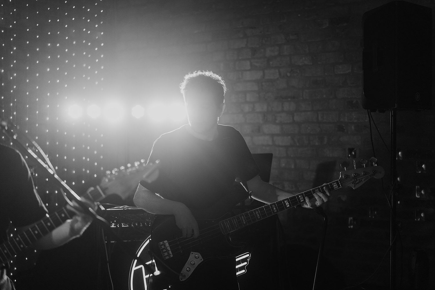 Drummer playing his drums with stage lightings behind while smiling.