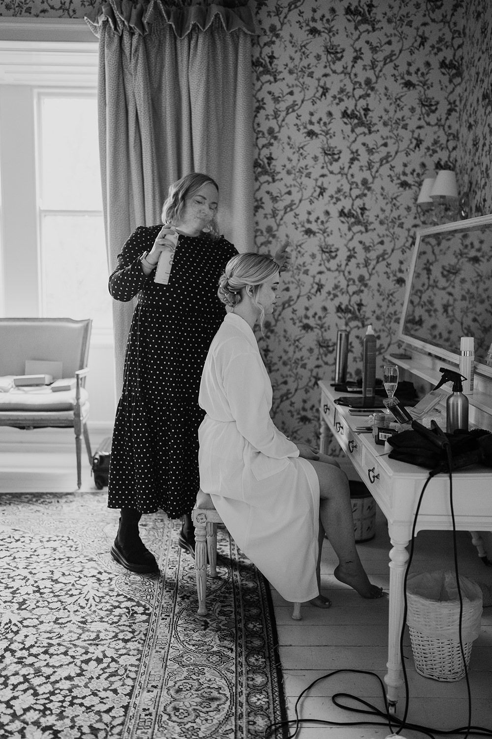 Bride sat having her hair styled on wedding morning.