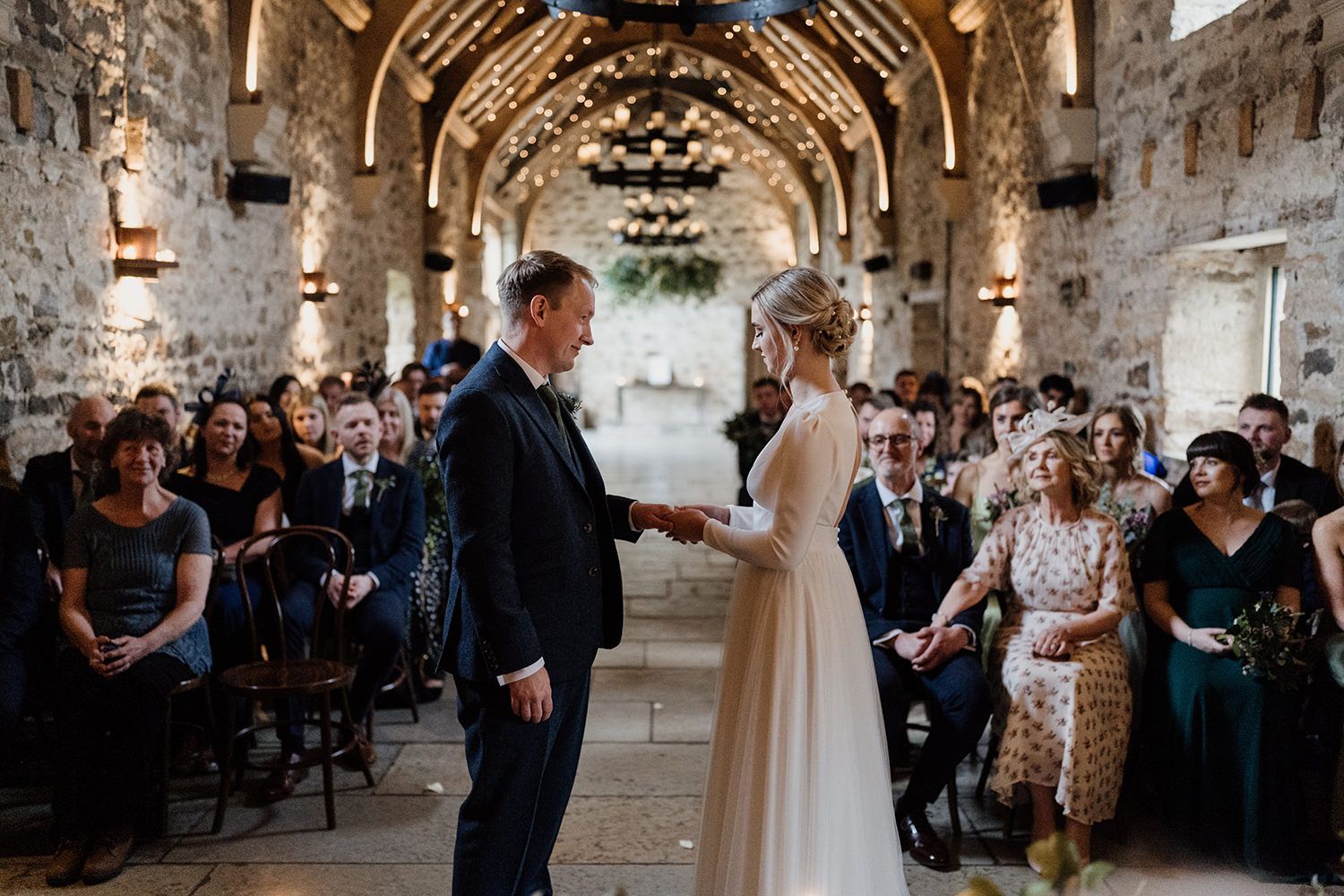 Bride giving wedding ring to groom at Healey Barn while the guests watch.