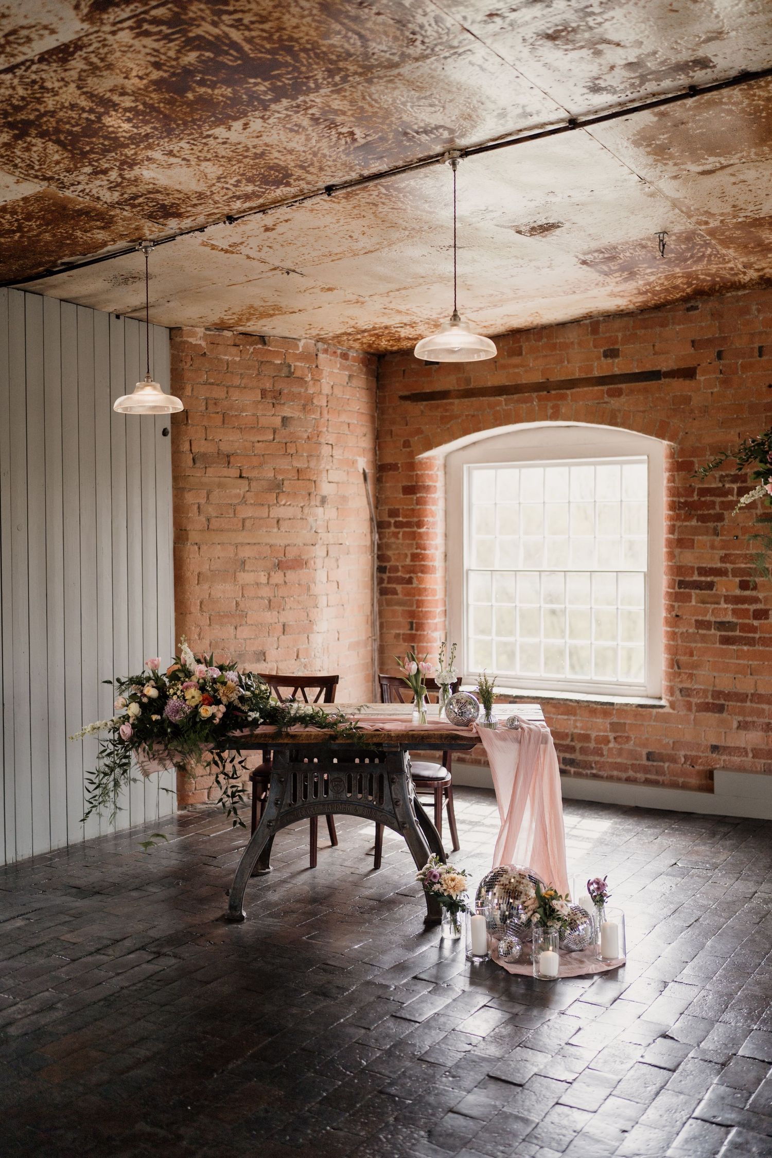 Rustic wedding reception setup with floral arrangements and pink accents.