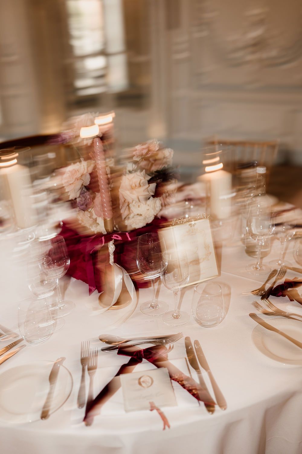 Elegant wedding table setting with blurred wine glasses and place settings in soft focus.
