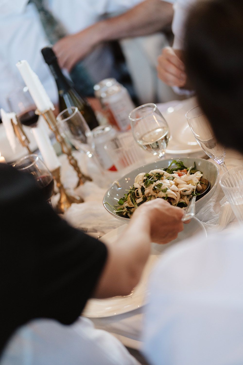 A table setting with wine glasses and a fresh salad being served during an elegant dining experience.
