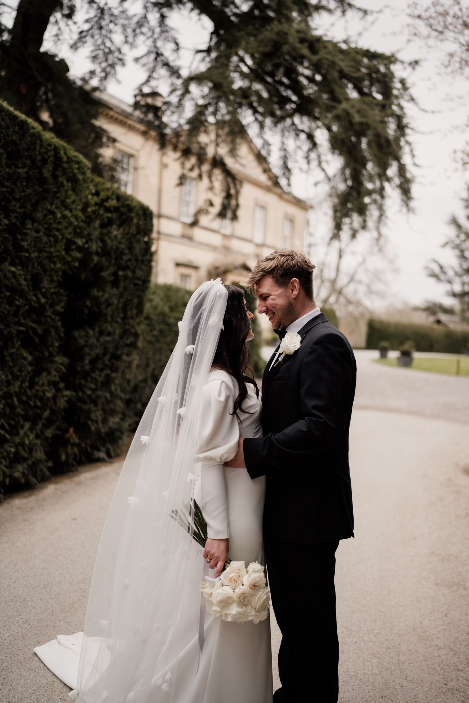 Couple dressed on their wedding day kissing with Middleton Lodge Estate in the background.