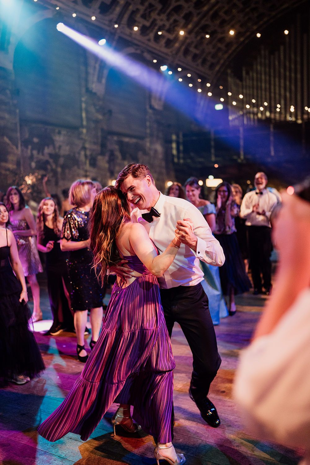 Groom dancing with a wedding guest in a purple dress.