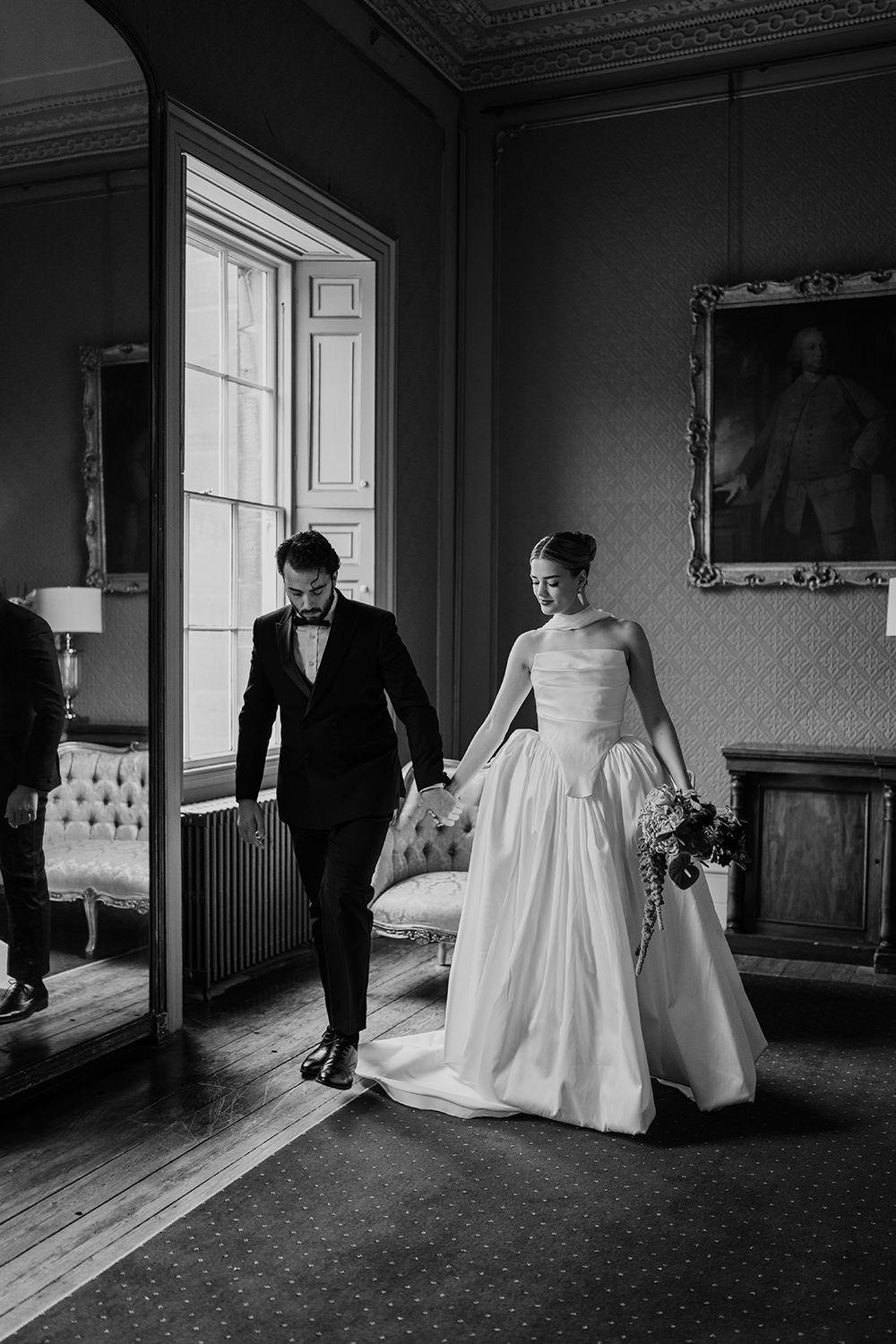 Editorial wedding portrait session: Bride and groom holding hands while looking towards each other.