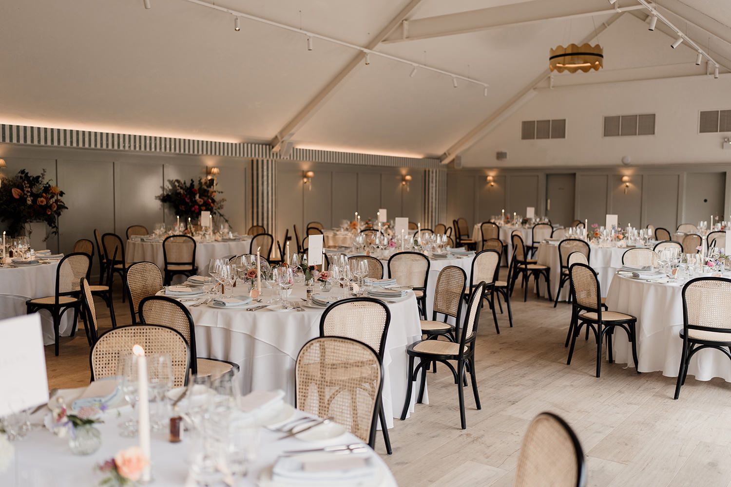 Kilvert Hall at Kin House styled with colourful flowers ready for wedding guests to sit down.
